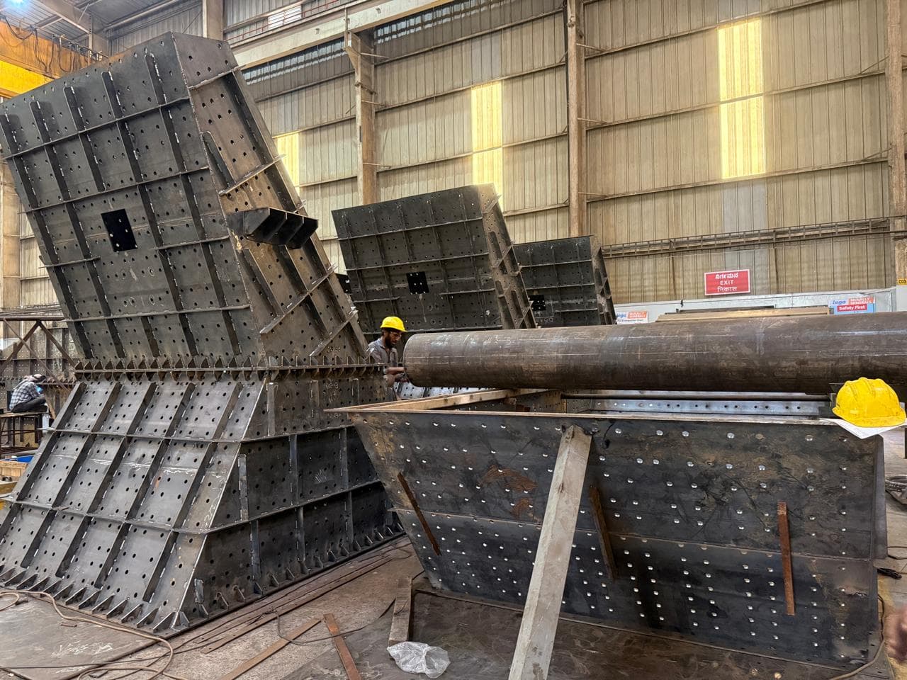 Large scale structural steel fabrication assembly with worker in safety helmet